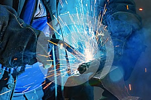 Welder in gloves welds a metal part in the factory.8