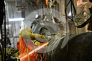 A welder is grinding weld joint on offshore pipeline