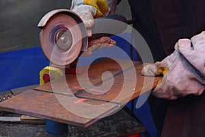 Welder hands grinding metal piece with a grinder, processing weld after welding, workshop