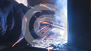 A welder in helmet doing his job. Welding process. Smoke and sparks. Close up