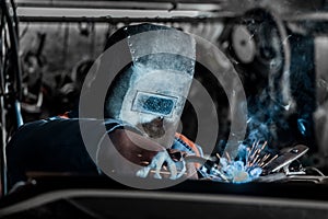 Welder industrial worker in the protective shield is engaged in welding and metal work at the plant