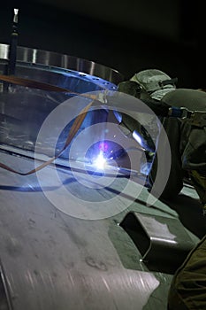 A welder joining two pieces of stainless steel.