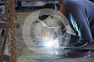 welder makes a velding metal structure sparks in a workshop