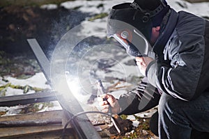Welder man welding metal iron with electrodes, worker wearing protective helmet and gloves. Close up of electrode welding and