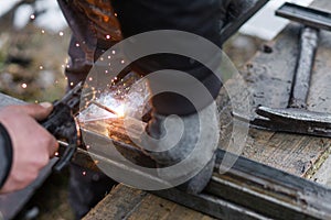 Welder man welding metal iron with electrodes, worker wearing protective helmet and gloves. Close up of electrode welding and