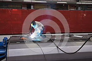 Welder man in work welding a steel sheet by TIG or WIG welding procedure, using a welding wire and inertal gas.