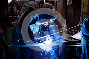 Welder in mask, in the process of welding metal with bright light, smoke and sparks