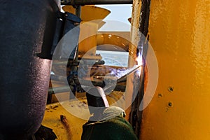 Welder perform welding to the metal plate at roof floor of manufacturing factory by using steel welding electrode in offshore oil