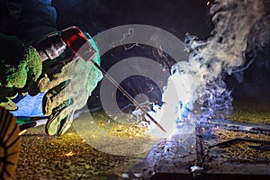 Welder perform welding to the metal plate at roof floor of manufacturing factory by using steel welding electrode in offshore oil