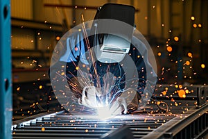 welder in protective gear creating sparks while welding metal