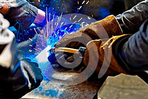 A welder in protective gloves produces a metal connection by electrical welding