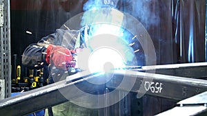 Welder with torch and protective helmet making bright sparks during welding