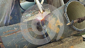 Welder uses arc welding pipe metal on site.