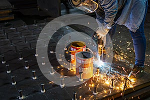 A welder is using a Stud Welding Machine to weld stud bolt on steel plate, at industrial factory