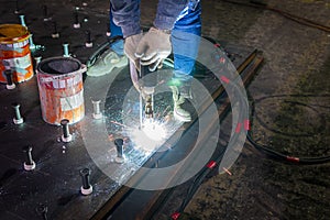 A welder is using a Stud Welding Machine to weld stud bolt on steel plate, at industrial factory