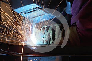 A welder using a wire feed welder to join two pieces of metal together.