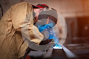 A welder with a welding machine works in a factory