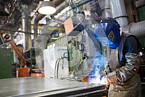 Welder welding metal at factory workshop