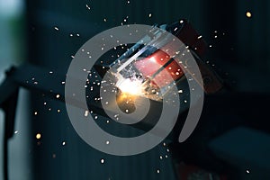 Welder is welding metal part with lots of sparks