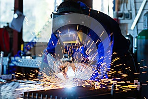 Welder welding metal in workshop with sparks photo