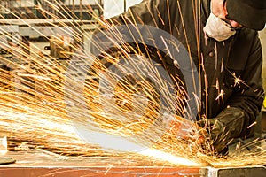 Welder welding metal in workshop with sparks