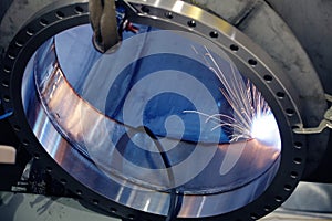 A welder welding a port onto a pressure vessel in a metal fabrication shop.