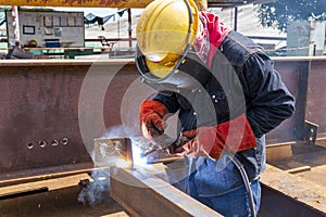 Welder is welding a steel plate for steel structure work with process Flux Cored Arc Welding& x28;FCAW& x29;