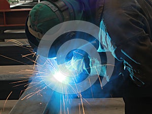 Welder is welding steel structure with all safety equipment in factory
