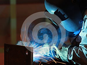 Welder is welding steel structure with all safety equipment in factory