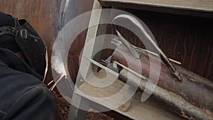 A welder welds gas pipes with an electrode when laying a main gas pipeline, close-up, industry.