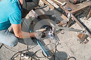 Welder welds metal structure. Construction worker at work. A working welder builds or repairs a new porch and facade of a building