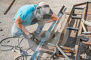 Welder welds metal structure. Construction worker at work. A working welder builds or repairs a new porch and facade of a building