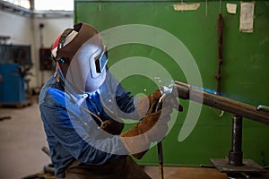 A welder welds a piece of metal in the factory, industrial work