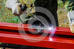 Welder welds steel closed profile. Arc welding outdoors photo
