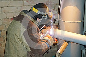 A welder welds technological pipelines with manual arc welding for an oil refinery in Russia. Welded joint