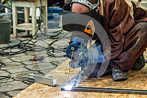 A welder at work assembles a metal structure from a shaped pipe