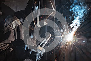 Welder at work in a factory. He is welding metal.