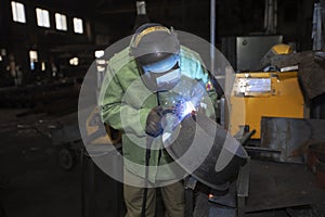 Welder at work. Man in a protective mask. The welder makes seams on the metal