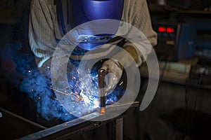 Welder at work. The welder heats the metal. Classes in the workshop.