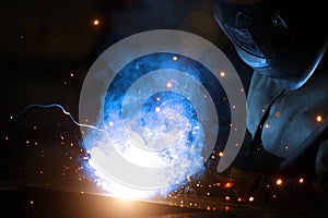 Welder at work. Welding of metal sparks and smoke in the workshop. Industrial Welder With gas Torch in Protective Helmet