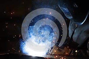 Welder at work. Welding of metal sparks and smoke in the workshop. Industrial Welder With gas Torch in Protective Helmet