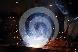 Welder at work. Welding of metal sparks and smoke in the workshop. Industrial Welder With gas Torch in Protective Helmet