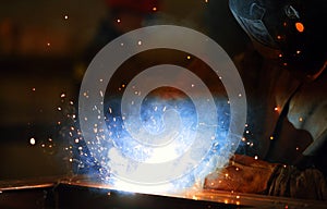 Welder at work. Welding of metal sparks and smoke in the workshop. Industrial Welder With gas Torch in Protective Helmet