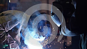 Welder at work. Welding of metal sparks and smoke in the workshop. Industrial Welder With gas Torch in Protective Helmet