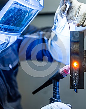 Welder worker welding a pieces of metal in the industrial factory, heavy weld industry concept