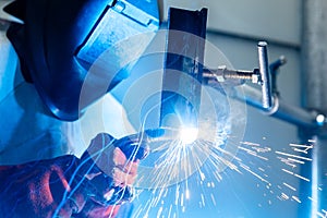 Welder worker welding a pieces of metal in the industrial factory, heavy weld industry concept