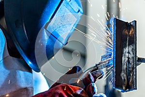 Welder worker welding a pieces of metal in the industrial factory, heavy weld industry concept