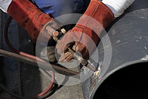 Welder worker welding a wide metal pipe tube with a oxy-fuel cutting torch