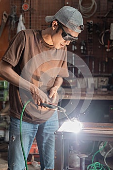 Welders stand up wearing black welding glasses when making metal racks