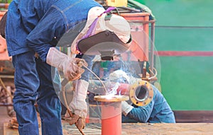 Welders are welding metal flange to connect with steel pipe for use improving oil pipeline systems work in tanker ship